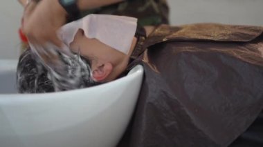 Erkek kuaför kadının saçını yıkıyor.