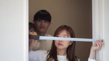 Parents and children measuring the room with a measure