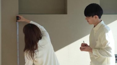 A couple measuring the room with a tape measure