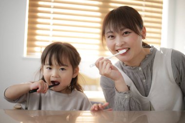 Ebeveynler ve çocuklar dişlerini fırçalıyor.