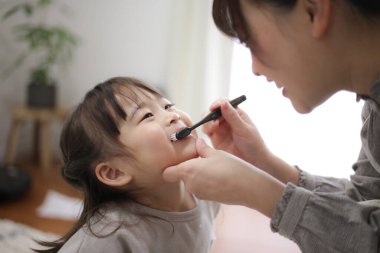 mother brushing child's teeth