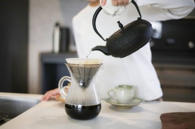 Demir çaydanlıkta kahve yapan bir kadın.