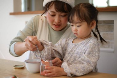 Aileler ve çocuklar kavanozlara ev yapımı reçel dolduruyorlar.