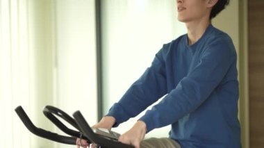 Evde spor bisikleti kullanan bir adam.