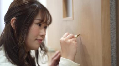 Bir kadın, kapıdaki bir çiziği kapatmak için tırnak kapağı kullanır.