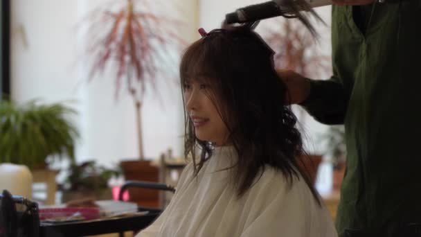 男性の美容師は女性の髪をアイロン — ストック動画