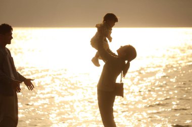 Ebeveyn ve çocuk sahilde oynuyorlar.