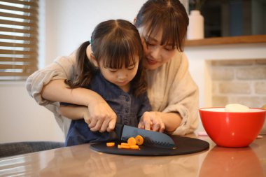 Ebeveyn ve çocuk havuç kesiyor.