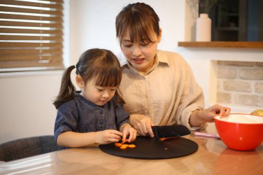 Ebeveyn ve çocuk havuç kesiyor.