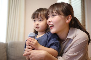 Ebeveynler ve çocuklar evde karaoke yapıyorlar.