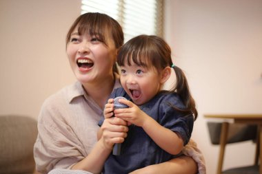 Ebeveynler ve çocuklar evde karaoke yapıyorlar.