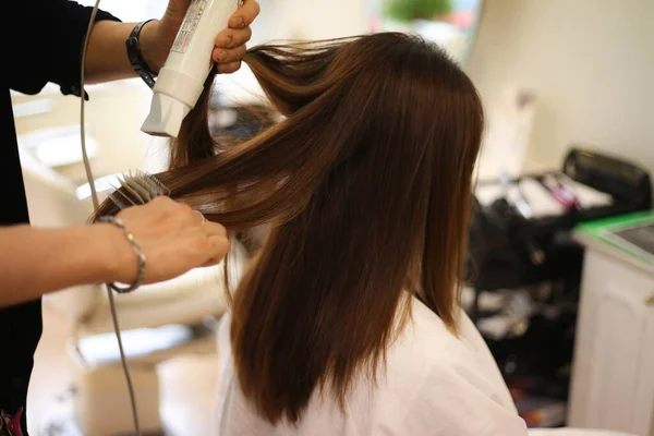 Male hairdresser applying hair dryer to woman's hair