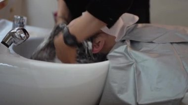 Erkek kuaför kadınların saçlarını yıkıyor.