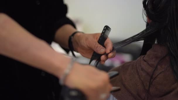 女性の髪にカーリングアイロンを塗布する男性の美容師 — ストック動画