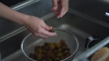 Bir kadın erik şurubundan alınan erik meyvesinden tohum topluyor.