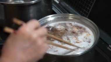 Bonito taneleriyle çorba yapan bir kadın.