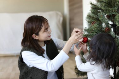 Ebeveynler ve çocuklar Noel ağacını süslüyorlar