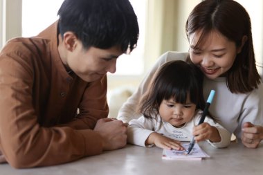 Ebeveynler ve çocuklar yeni yıl kartı yazıyor.