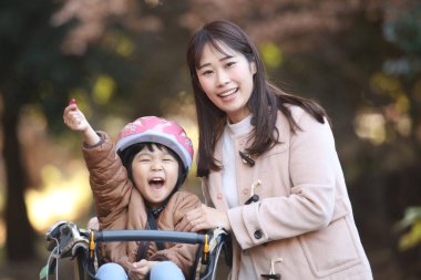 Anne ve baba bisiklete biniyor.