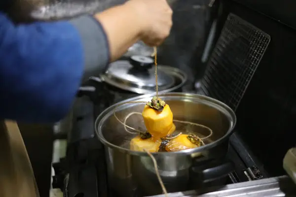 Eine Frau Taucht Kaki Kochendes Wasser — Stockfoto