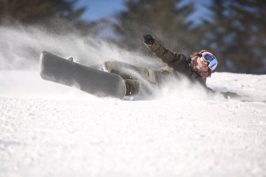 Kadın snowboardcu düşüyor.