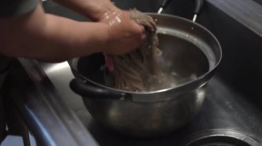 Haşlanmış soba eriştesini durulayan bir kadın.