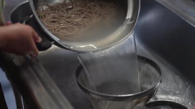 Kaynamış soba eriştesinin suyunu emiyor.
