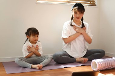 Aileler ve çocuklar evde yoga yapıyorlar.