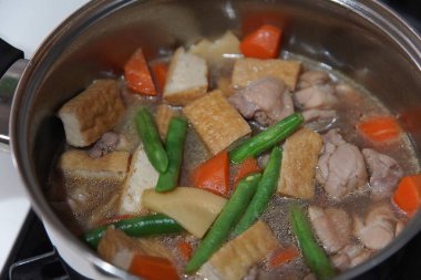 Cooking stew of chicken thighs, bamboo shoots and deep-fried tofu clipart