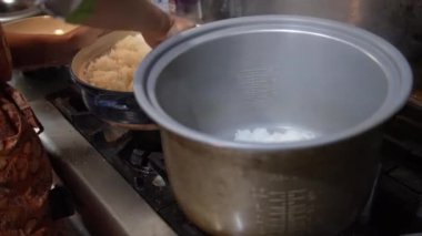 Termos kavanozuna kilden yapılmış bir tencerede pilav koyan bir kadın.