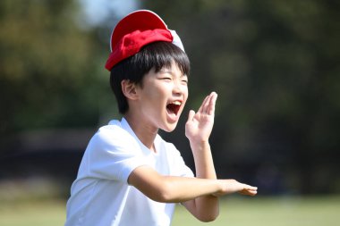 Kafasında kırmızı beyaz bir şapkayla oynayan bir çocuk.