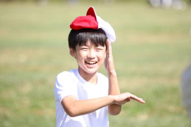 Kafasında kırmızı beyaz bir şapkayla oynayan bir çocuk.