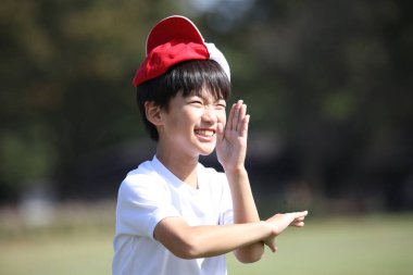 Kafasında kırmızı beyaz bir şapkayla oynayan bir çocuk.