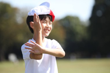 Kafasında kırmızı beyaz bir şapkayla oynayan bir çocuk.