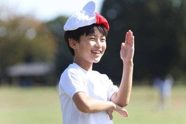 Kafasında kırmızı beyaz bir şapkayla oynayan bir çocuk.