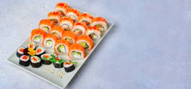 Suşi, somon ve açık mavi arka planda karides, çiçek şekilli Maki suşi ruloları, Japon mutfağı.