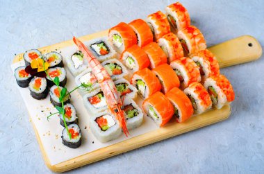 Suşi, somon ve açık mavi arka planda karides, çiçek şekilli Maki suşi ruloları, Japon mutfağı.