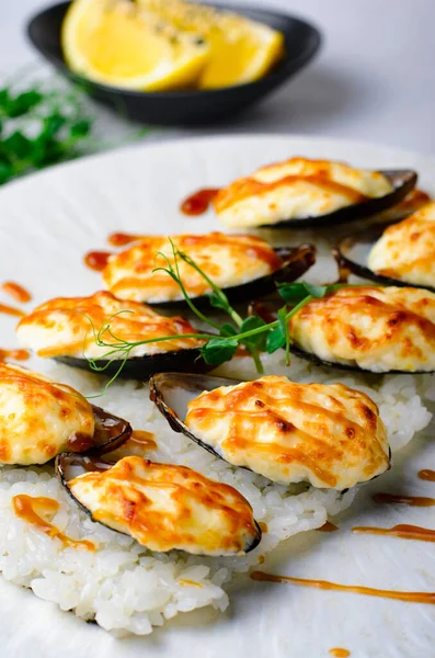 Baked mussels with cheese in shells on rice in a plate, gourmet dinner
