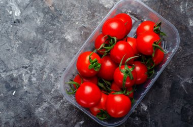 Karanlık Arkaplanda plastik bir kapta kiraz domatesleri, Yakın plan