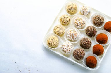 Çeşitli vejetaryen tatlılar, tohumlu lezzetli şeker topları, kurutulmuş meyve ve kakao tozu, Chia ile sağlıklı şeker, Susam tohumu, Hindistan cevizi ve yer mantarı.