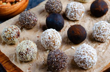 Assorted vegan sweets, Delicious Candy Balls with seeds, dried fruit, nuts, and cocoa powder, Healthy Candies with Chia, Sesame Seeds, Coconut and Truffles on wooden background