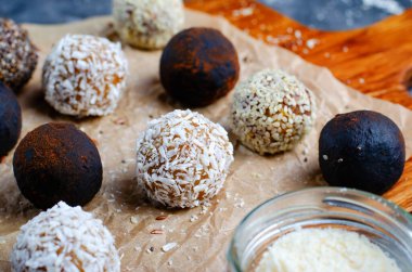 Assorted vegan sweets, Delicious Candy Balls with seeds, dried fruit, nuts, and cocoa powder, Healthy Candies with Chia, Sesame Seeds, Coconut and Truffles on wooden background