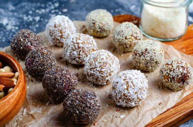 Assorted vegan sweets, Delicious Candy Balls with seeds, dried fruit, nuts, and cocoa powder, Healthy Candies with Chia, Sesame Seeds, Coconut and Truffles on wooden background