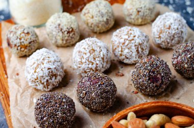 Assorted vegan sweets, Delicious Candy Balls with seeds, dried fruit, nuts, and cocoa powder, Healthy Candies with Chia, Sesame Seeds, Coconut and Truffles on wooden background