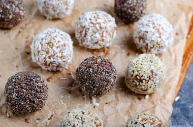 Assorted vegan sweets, Delicious Candy Balls with seeds, dried fruit, nuts, and cocoa powder, Healthy Candies with Chia, Sesame Seeds, Coconut and Truffles on wooden background