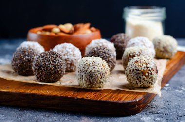 Assorted vegan sweets, Delicious Candy Balls with seeds, dried fruit, nuts, and cocoa powder, Healthy Candies with Chia, Sesame Seeds, Coconut and Truffles on wooden background