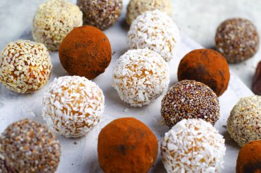 Çeşitli vejetaryen tatlılar, tohumlu lezzetli şeker topları, kurutulmuş meyve ve kakao tozu, Chia ile sağlıklı şeker, Susam tohumu, Hindistan cevizi ve yer mantarı.