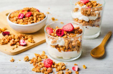 Granola and Yogurt Parfaits, Healthy Breakfast, Muesli with Dried Berries on Bright Concrete Background