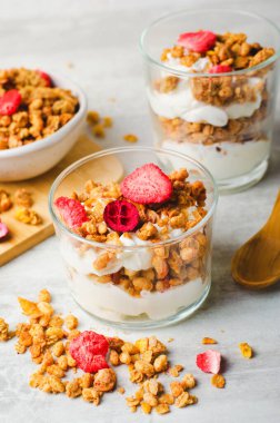 Granola and Yogurt Parfaits, Healthy Breakfast, Muesli with Dried Berries on Bright Concrete Background