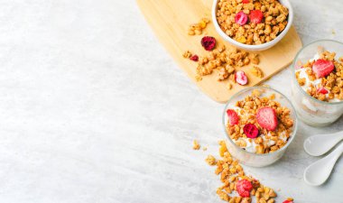 Granola and Yogurt Parfaits, Healthy Breakfast, Muesli with Dried Berries on Bright Concrete Background